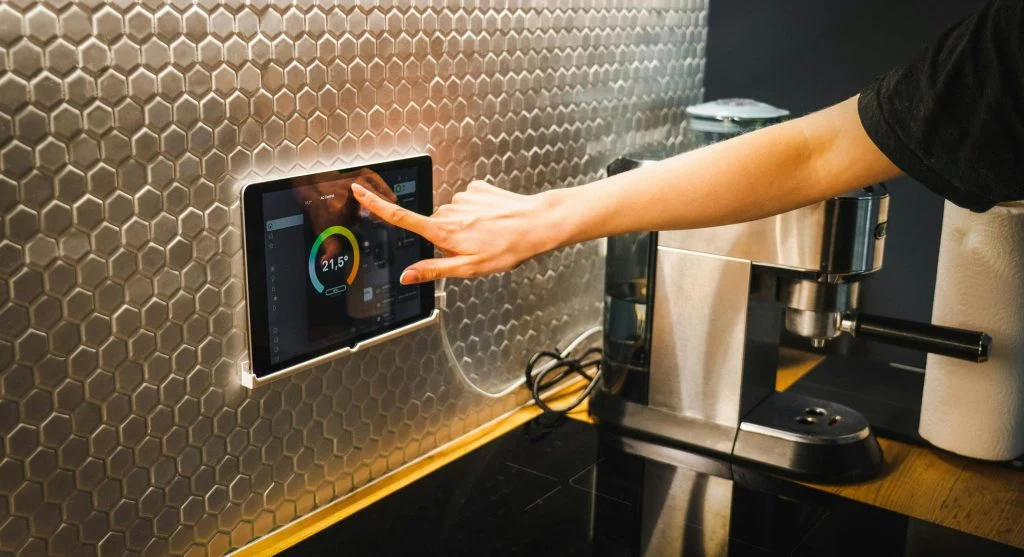 Smart thermostat on a wall with a smartphone in the background