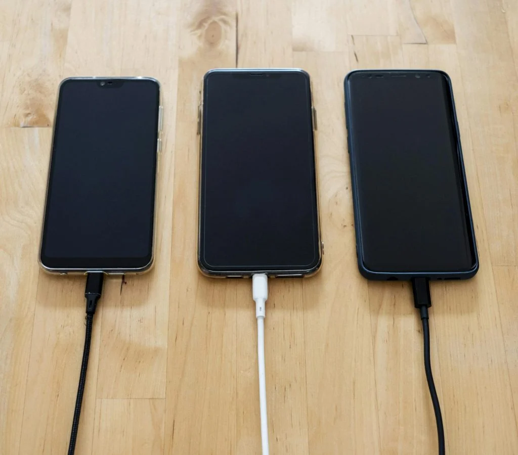 Smartphone connected to a third-party charger with a warning sign