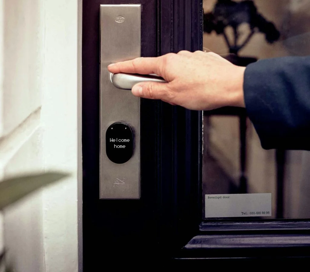 Smart lock device on a front door with a smartphone in the background