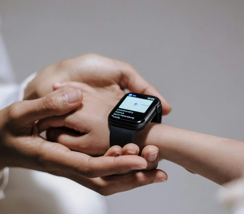 Woman wearing a smartwatch, with a smartphone and laptop in the background